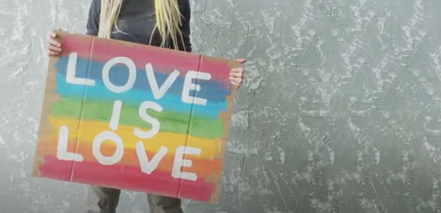 female holding love is love sign