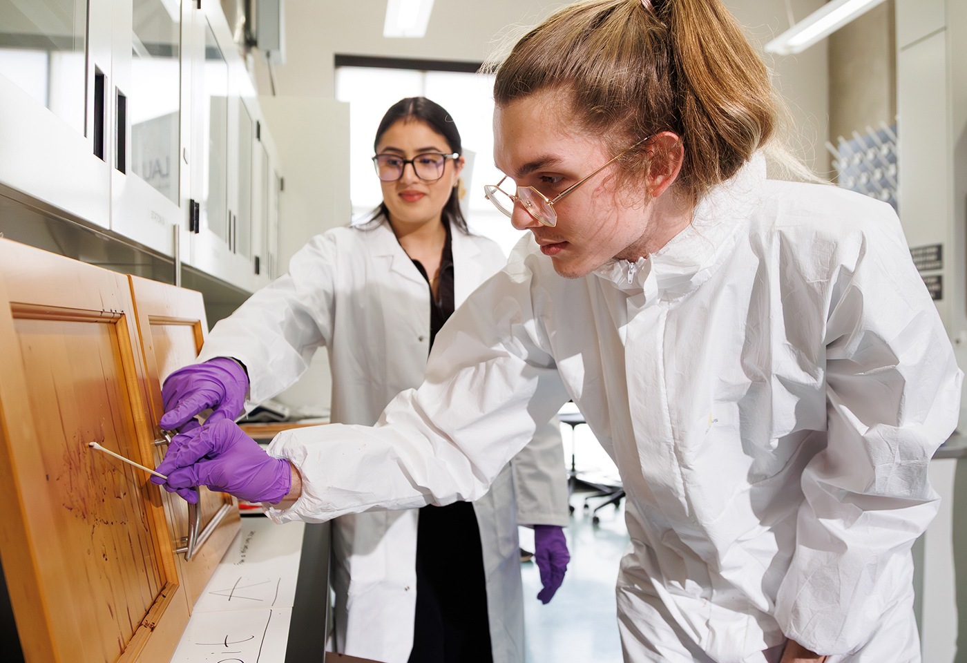 A student participant swabs a sample of evidence in Laurier Brantford's forensics lab