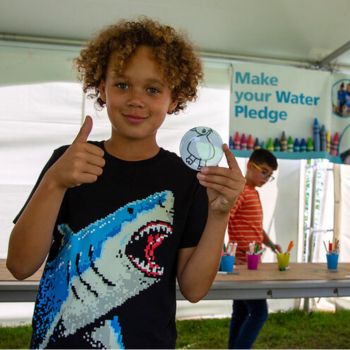 A smiling child gives a thumbs up. 